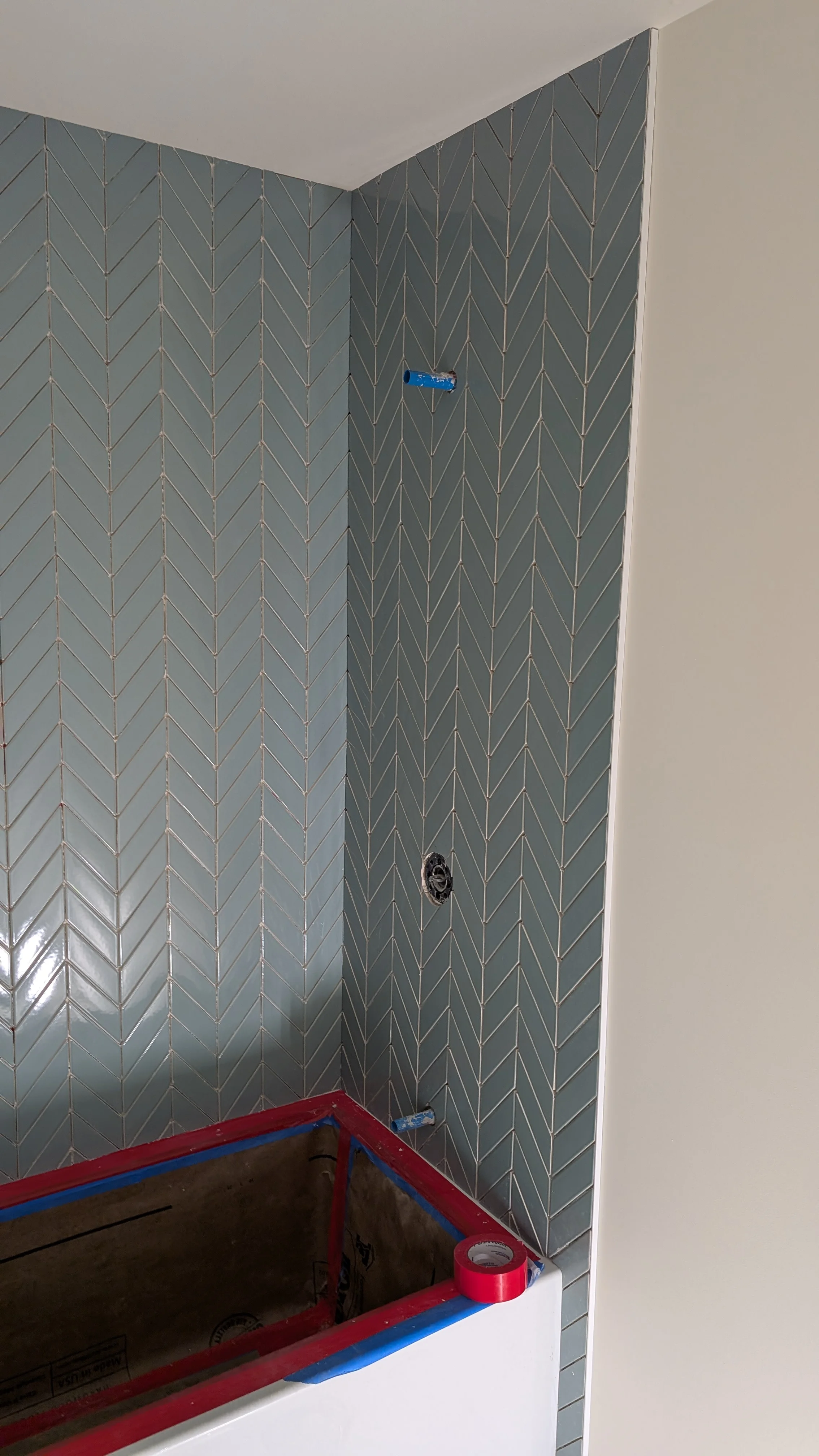 Gray herringbone tile shower walls with electrical outlet boxes during bathroom remodel