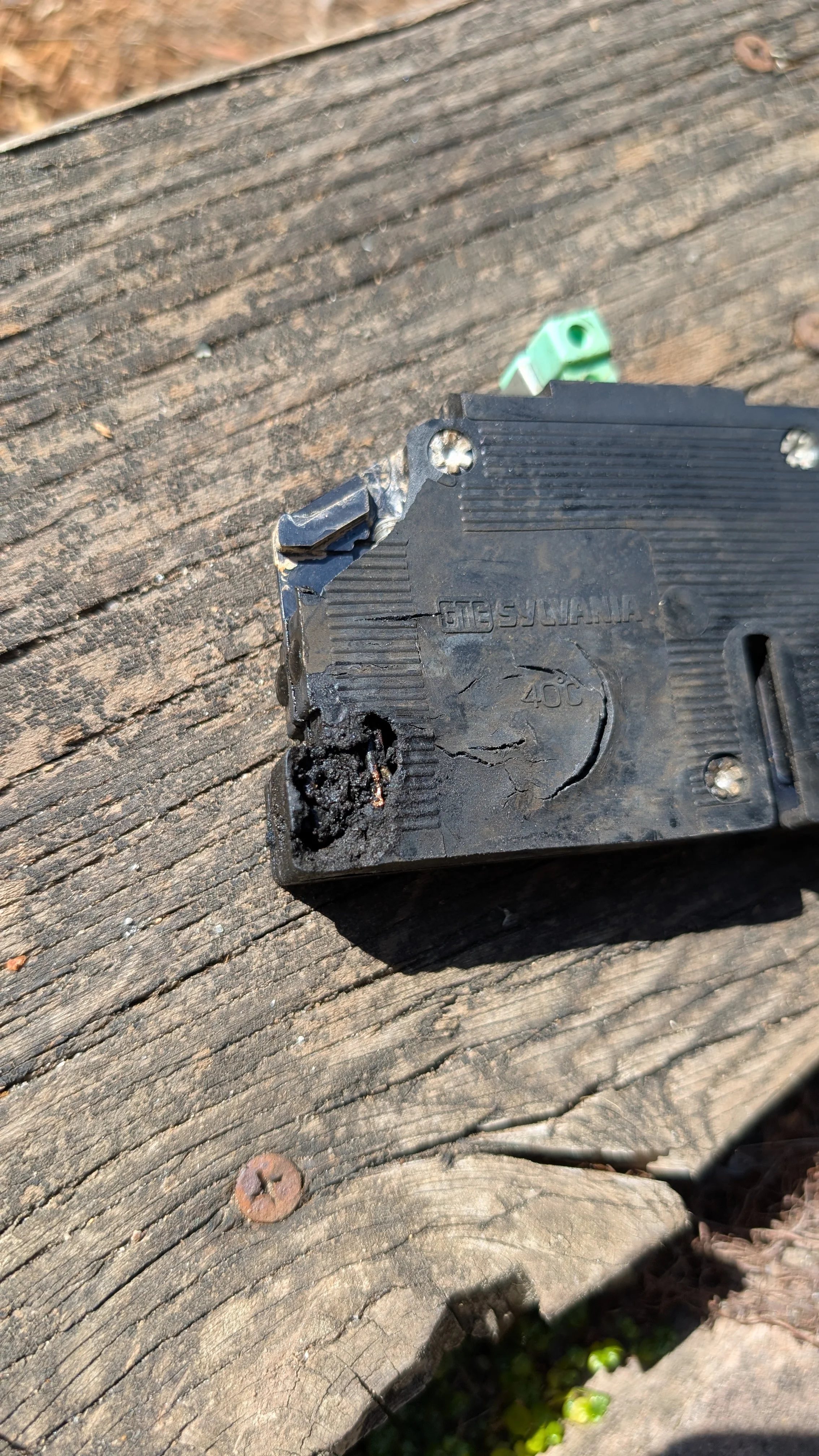 Damaged electrical breaker panel on wooden deck with corroded metal housing