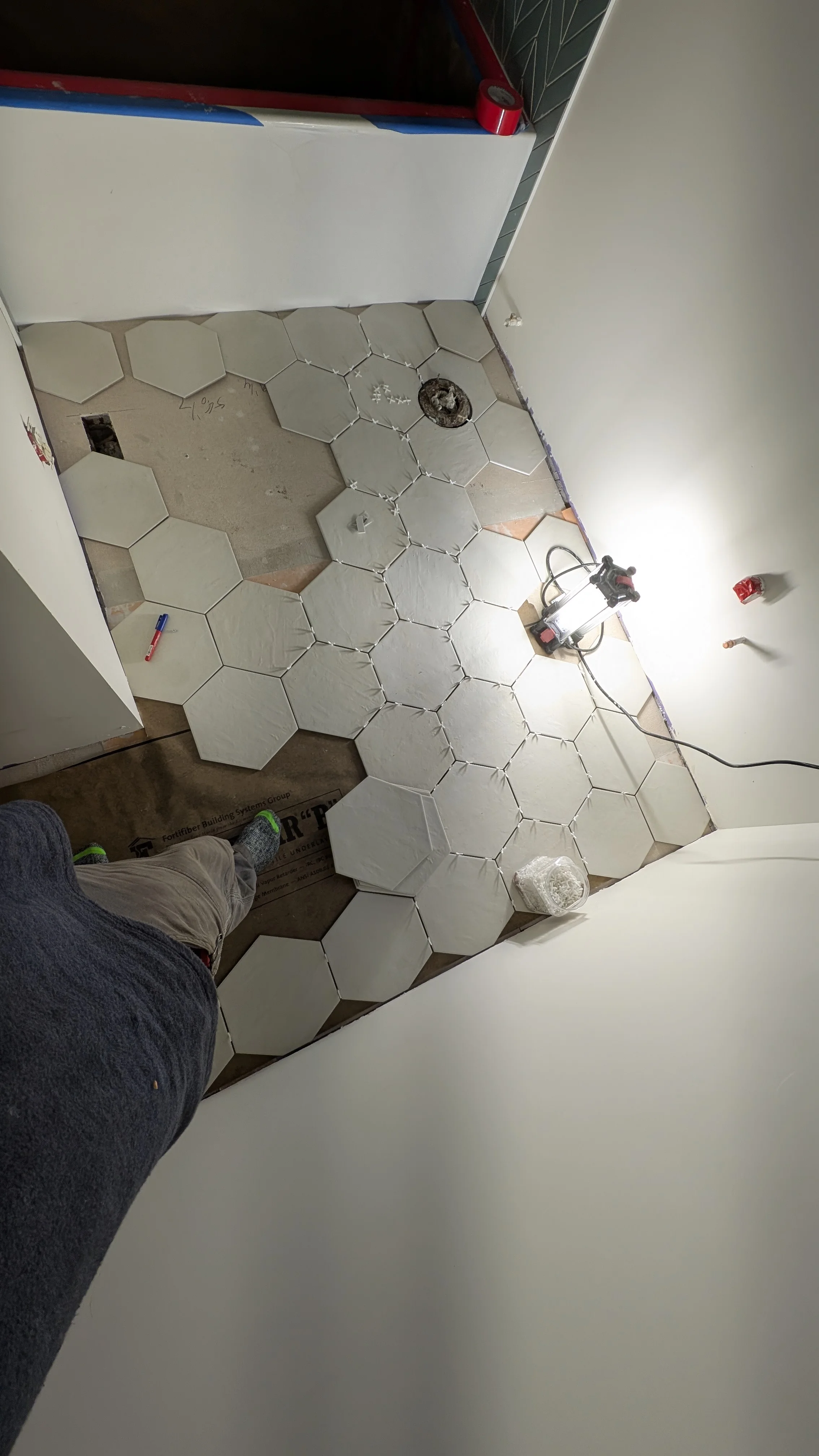 Bathroom floor with hexagonal tile installation and electrical rough-in work in progress